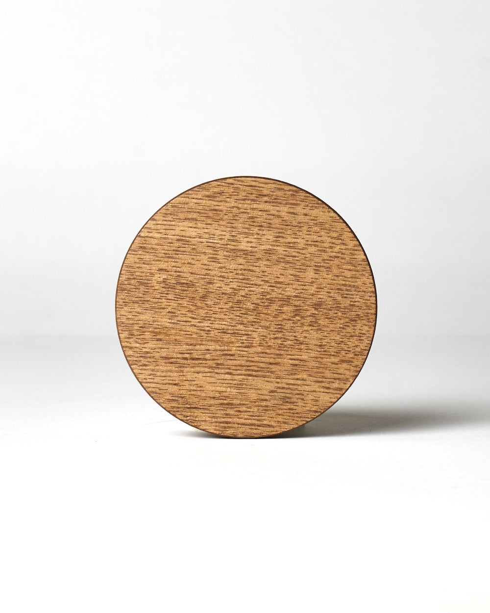 A circular wooden candle cover with visible grain patterns against a white background.