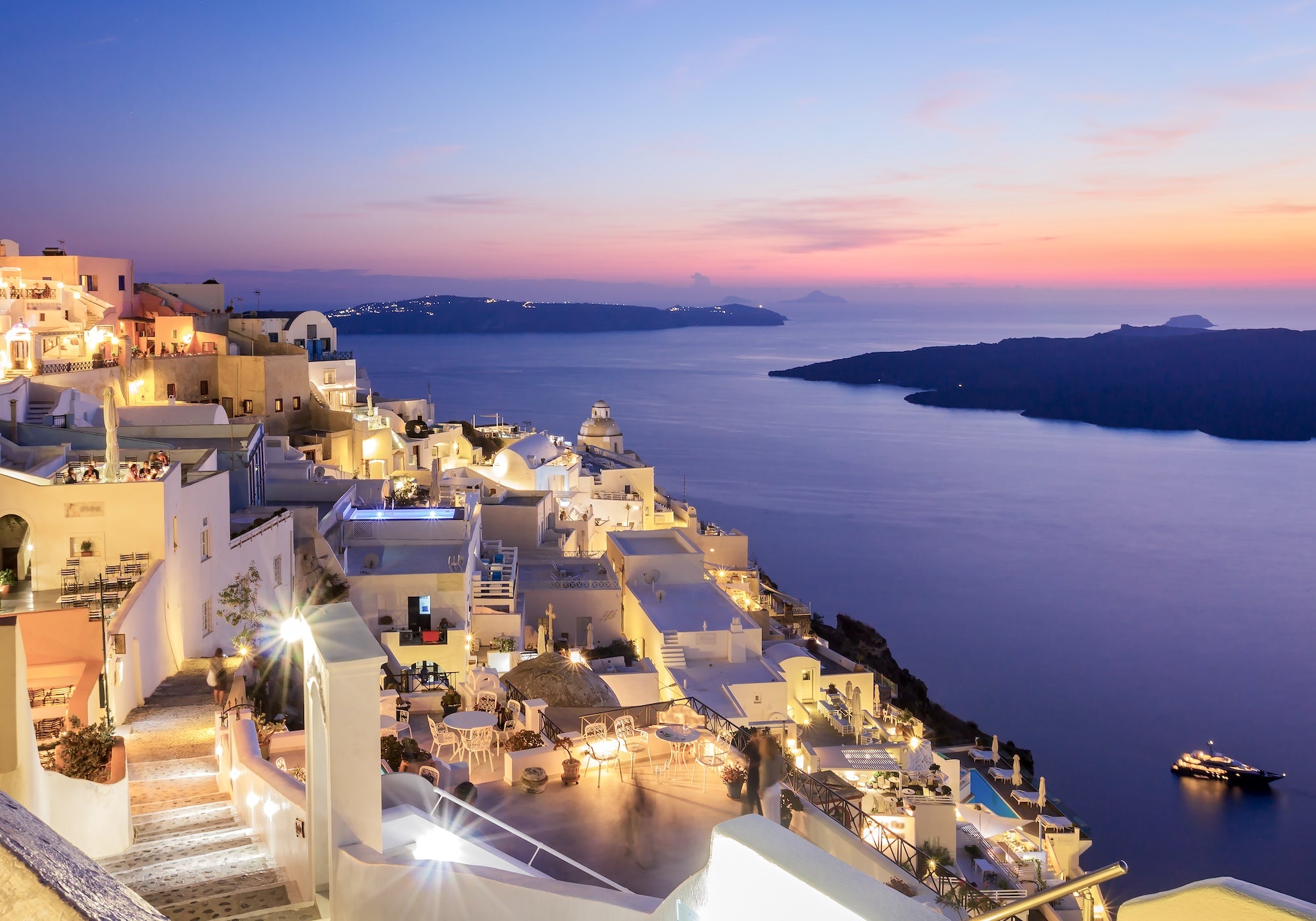 Inspiration image of the famous white town set in front of a moody sunset sky over the water.